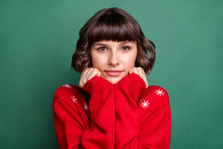 Portrait of attractive peaceful brown-haired girl wearing festal warm sweater enjoying isolated over...