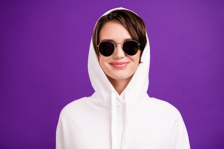 Photo of shiny adorable young lady wear white jumper dark eyewear smiling isolated purple color backgroundの写真素材