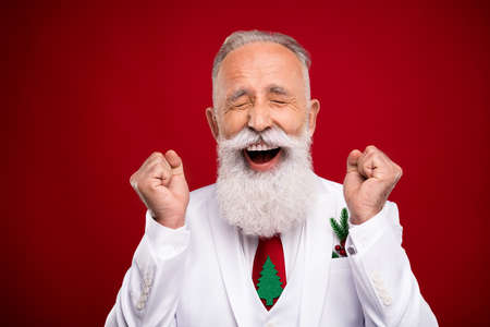 Photo of funny aged white beard man hands fists yell wear white jacket isolated on red color backgroundの写真素材