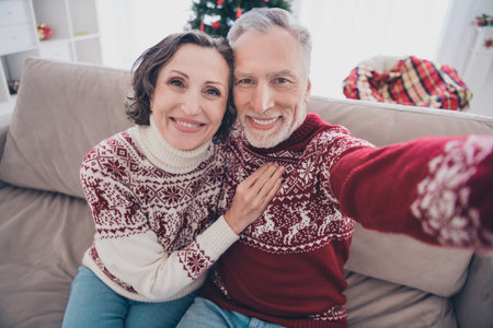 Photo of sweet cute mature lovers wear knitted sweaters smiling hugging tacking selfie indoors house home roomの写真素材