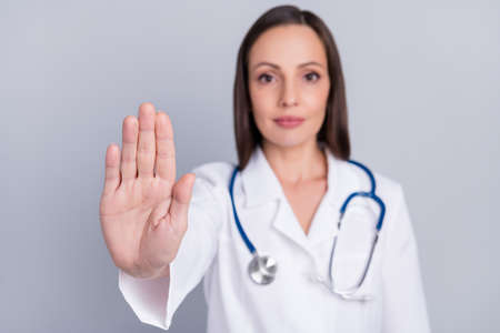 Photo of pretty confident woman doc dressed white coat rising palm asking stop isolated grey color...