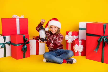 Full body photo of happy small girl hold hand lantern enjoy holiday present box isolated on yellow color backgroundの写真素材
