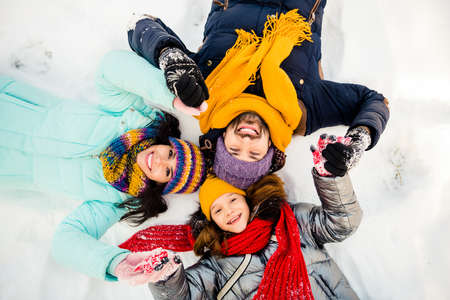 High angle view photo of happy excited cheerful family lying on ground snow having fun winter holiday vacationの写真素材