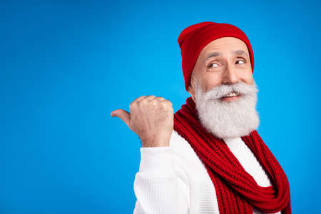 Photo of cheerful man look interested indicate thumb empty space promotion isolated on blue color...
