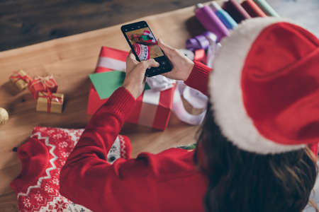 Photo of cute shiny young lady wear knitted sweater hat tacking photo of presents indoors house home roomの写真素材