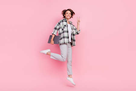 Full size photo of funny young brunette lady jump hold laptop wear shirt trousers shoes isolated on...