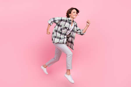 Full body profile side photo of young woman happy positive smile jump go walk run fast isolated over pink color backgroundの写真素材