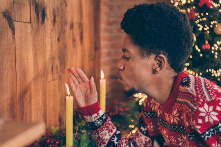 Photo of charming sweet dark skin guy dressed print pullover blowing candle indoors house home roomの写真素材