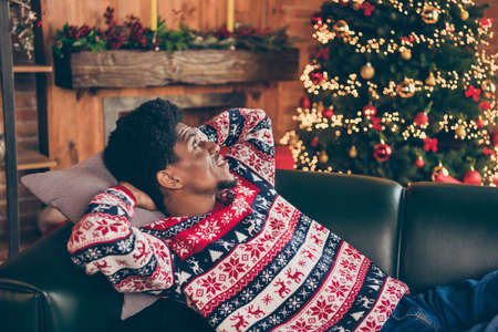 Photo portrait man laying on sofa relaxing on xmas holidays near decorated treeの写真素材