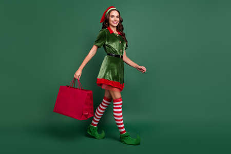 Full body profile side photo of young girl happy positive smile go walk shop season sale store isolated over green color backgroundの写真素材