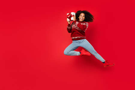 Photo of pretty funny lady wear print pullover jumping high holding present empty space isolated red...