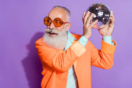 Photo of retired pensioner positive man hand hold disco ball clubber sunglass cool isolated on violet color backgroundの写真素材