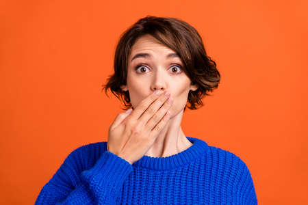 Photo of stressed brunette hair millennial lady close mouth wear blue sweater isolated on orange color backgroundの写真素材