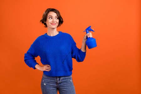 Photo portrait woman keeping pulverizer watering plants looking empty space isolated orange color background copyspaceの写真素材