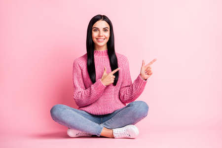 Full length portrait of charming cheerful lady lotus pose direct fingers empty space isolated on pink color backgroundの写真素材