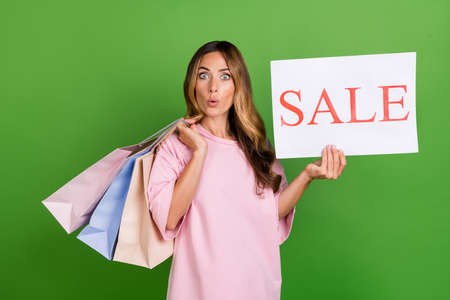 Photo of shiny excited woman dressed pink t-shirt dark eyewear holding shopping bags sale placard...