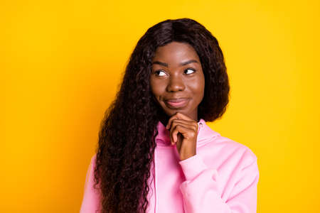 Photo portrait of african american girl thinking looking at blank space isolated on vivid yellow colored backgroundの写真素材