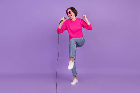 Full size photo of elderly woman happy positive smile sing song mic concenrt star isolated over purple color backgroundの写真素材