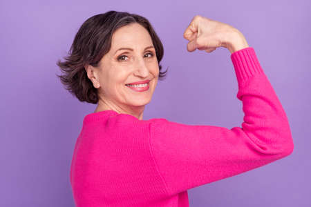 Profile side photo of aged woman happy smile show hand muscles strong isolated over violet color backgroundの写真素材