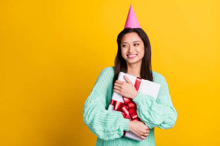 Photo of charming cheerful nice young woman look empty space hug gift birthday isolated on yellow color backgroundの写真素材