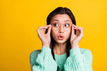Photo of amazed shocked young woman look empty space wear glasses isolated on yellow color backgroundの写真素材