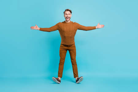 Full size photo of attractive young happy funny man open hands good mood isolated on blue color backgroundの写真素材