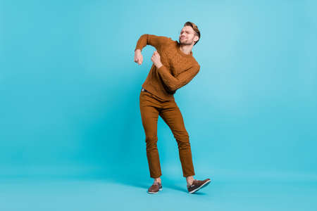 Full length photo of cheerful funky young man good mood dance wear casual outfit isolated on blue color backgroundの写真素材