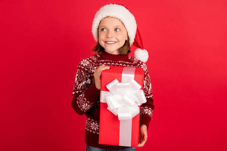 Portrait of attractive cute cheerful girl holding gift festal occasion newyear isolated over bright red color backgroundの写真素材