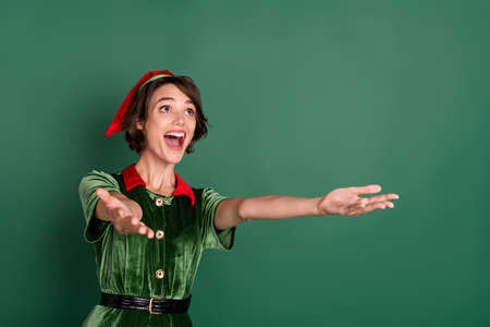 Portrait of attractive cheerful girl catching copy space offer bargain newyear day isolated over green color backgroundの写真素材