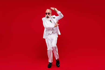 Full body photo of funny happy old man dance good mood wear three piece suit xmas isolated on red color backgroundの写真素材