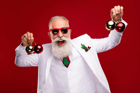 Photo of happy charming old man hold hands baubles christmas tree smile showman isolated on red...