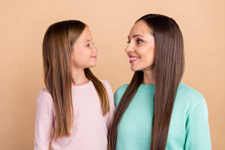Portrait of two attractive cute sweet tender cheerful girls hugging care trust isolated over beige pastel color backgroundの写真素材