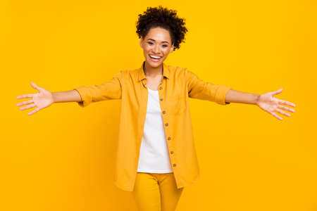 Photo of young cheerful african woman open arms glad embrace invite isolated over yellow color backgroundの写真素材