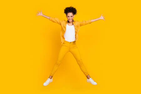 Full length body size photo woman jumping up playful happy isolated vivid yellow color backgroundの写真素材