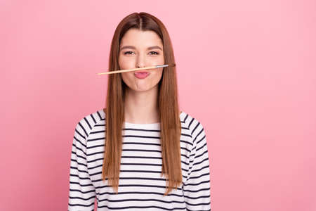 Portrait of attractive cheerful funny girl holding brush like mustache fooling isolated over pink pastel color backgroundの写真素材