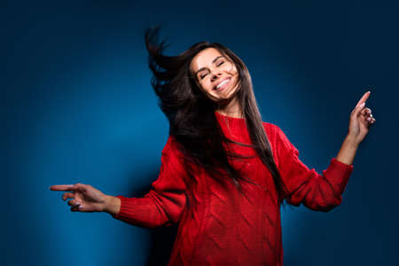 Photo portrait of girl smiling dancing overjoyed at party in red sweater isolated on dark blue color...