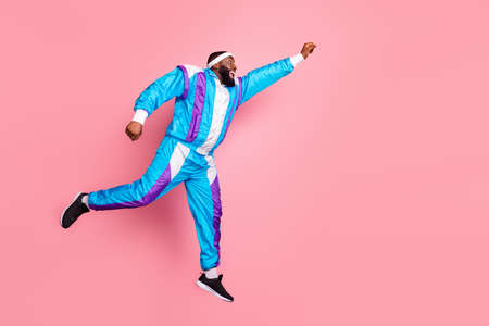 Full body profile side photo of young black man happy positive smile jump run superhero isolated over pink color backgroundの写真素材