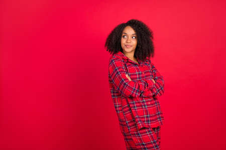 Photo of dreamy stylish trendy young afro american woman model hands folded look empty space isolated on red color backgroundの写真素材