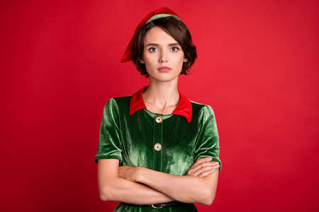 Photo of serious young charming woman santa helper new year wear hat elf isolated on red color backgroundの写真素材
