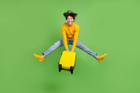 Full length body size photo jumping man keeping luggage in airport isolated pastel green color backgroundの写真素材