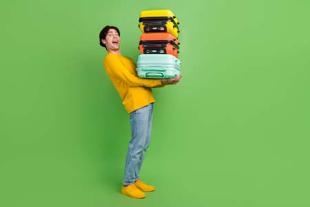 Full length body size photo man keeping heavy bags in airport isolated pastel green color backgroundの写真素材
