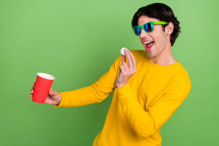 Photo portrait man wearing sunglass playing beer pong at party isolated pastel green color backgroundの写真素材