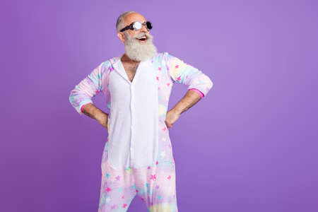 Portrait of attractive cheerful man wearing pajama pilot specs hands on hips isolated over violet purple color backgroundの写真素材