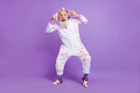 Full body photo of happy cool old man wear nightwear hands hood enjoy isolated on purple color backgroundの写真素材