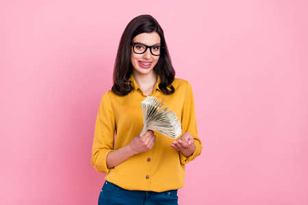 Photo of nice brunette hairdo millennial lady hold money wear yellow shirt eyewear isolated on pink color backgroundの写真素材