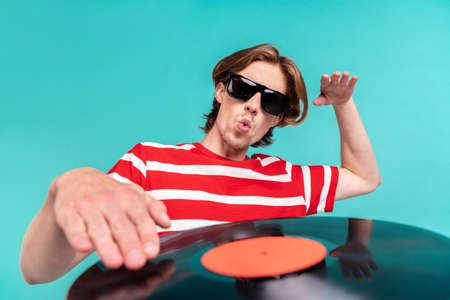 Portrait of attractive funky amazed guy playing vinyl disk having fun party isolated over bright teal turquoise color backgroundの写真素材