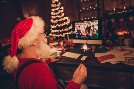 Profile side photo of aged santa claus look monitor video call family christmas time lights atmosphere magic decor indoorsの写真素材
