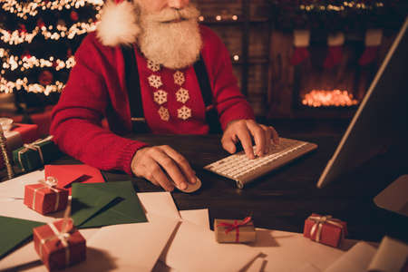Cropped photo portrait santa claus typing message using keyboard sitting at table in winterの写真素材