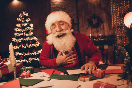 Photo portrait cheerful smiling santa wearing glasses headwear sweater laughing preparing gifts for xmasの写真素材