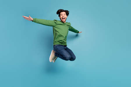 Full size photo of excited crazy cheerful man feeling freedom jumping in air isolated on blue color backgroundの写真素材
